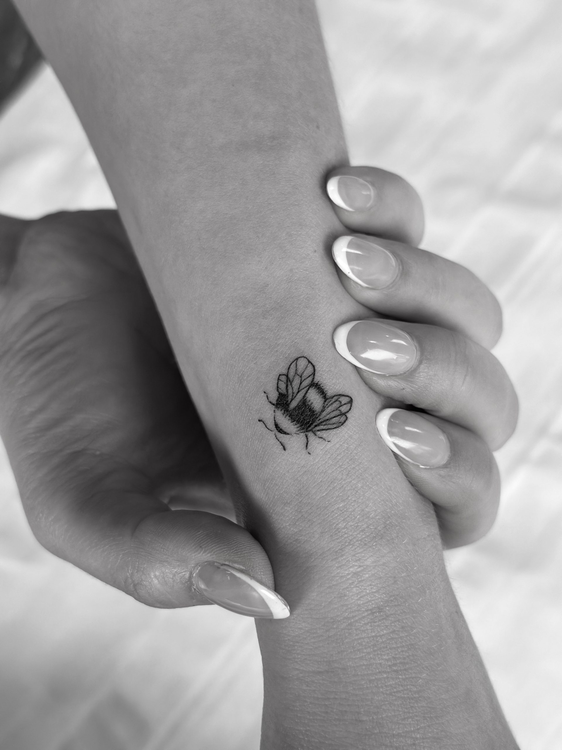 Black and white fly tattoo on forearm with manicured nails Black and white fly tattoo on forearm with manicured nails